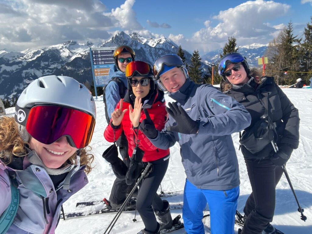 Leden van Rotary Club Amersfoort Young Ambition op de piste in Flachau met besneeuwde bergen op de achtergrond