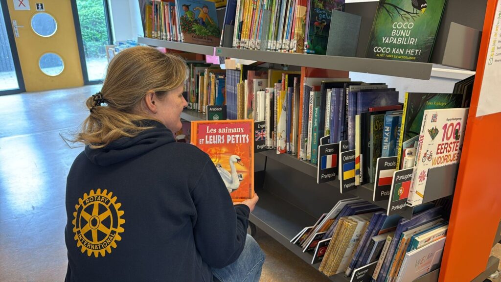 Een RAYA-lid in de bibliotheek van Wereldwijzer Taalschool bekijkt een meertalig kinderboek